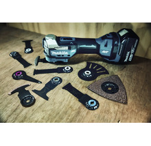 Makita Akku-Multitool mit verschiedenen Starlock-Aufsätzen wie Sägeblättern und Schleifplatte auf einer Holzoberfläche.