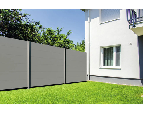 Grauer Sichtschutzzaun aus horizontalen Paneelen im Garten neben einem weißen Haus auf einer Rasenfläche.