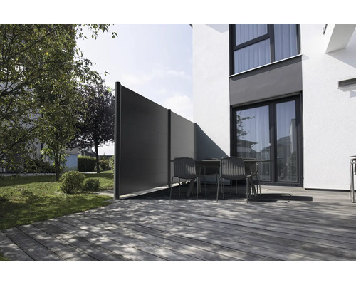 Moderner Sichtschutz aus Paneelen auf einer Terrasse mit Holzdeck und Gartenmöbeln vor einem Wohnhaus.