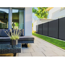 Moderner Sichtschutzzaun in Anthrazit auf einer organisierten Terrasse mit grauen Bodenplatten, Gartenmöbeln aus Geflecht und einer Rasenfläche.