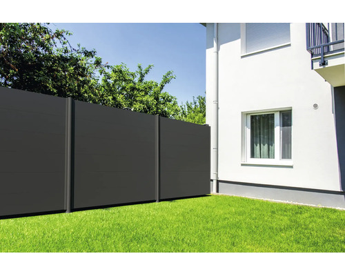 Moderner Sichtschutzzaun aus dunklen Paneelen im Garten auf einer Rasenfläche neben einem Wohnhaus.