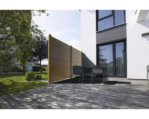 Sichtschutzzaun aus Paneelen auf einer Holzterrasse vor einem modernen Haus mit Gartenmöbeln und Garten.