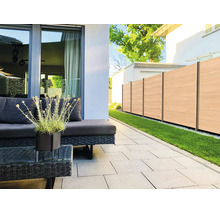 Modern gestaltete Terrasse mit hellgrauen Bodenplatten, dunklen Polyrattan-Gartenmöbeln und einem Sichtschutzzaun in Holzoptik.