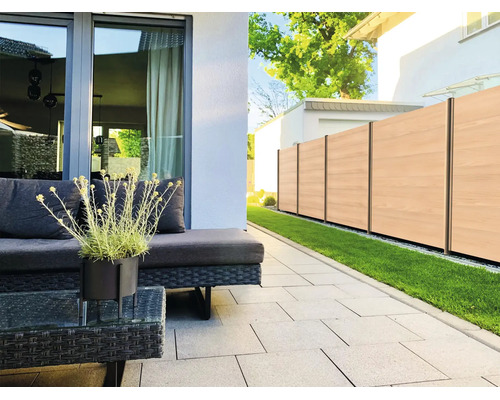 Modern gestaltete Terrasse mit hellgrauen Bodenplatten, dunklen Polyrattan-Gartenmöbeln und einem Sichtschutzzaun in Holzoptik.