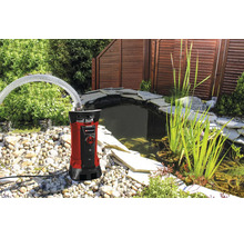 Einhell Schmutzwasserpumpe mit Schlauch an einem Gartenteich mit Steinen und Pflanzen.