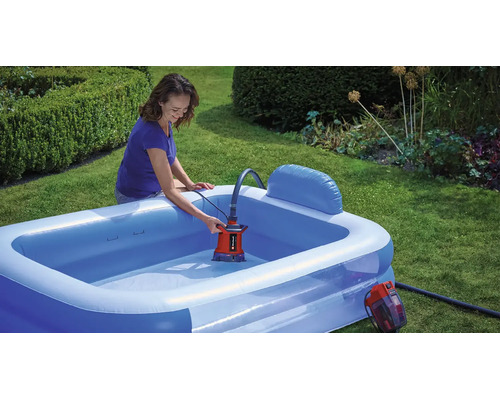 Eine Frau entleert einen aufblasbaren Pool im Garten mit einer Akku-Tauchpumpe von Einhell.
