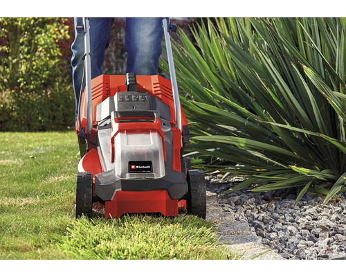 Einhell Akku-Rasenmäher beim präzisen Mähen einer Rasenkante an einem Beet im Garten.
