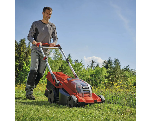 Ein Mann mäht mit einem Einhell Akku Rasenmäher eine Wiese bei sonnigem Wetter.