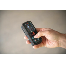 Hand hält einen Bosch Laser Entfernungsmesser mit digitalem Display für präzise Messungen.