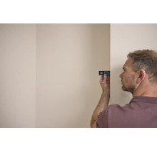 Ein Mann verwendet einen digitalen Laserentfernungsmesser von Bosch gegen eine Wand, um eine Distanz zu messen.