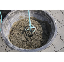 Beton mischen im Mörtelkübel mit einem Rührwerk auf Pflastersteinen.