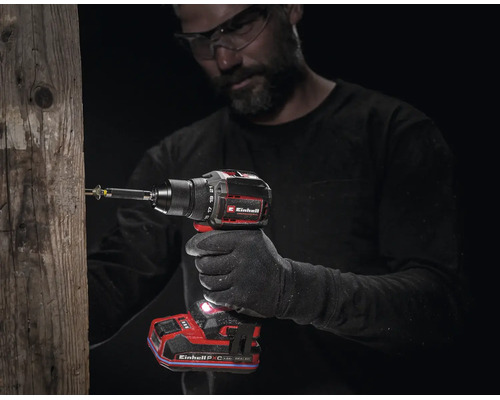 Handwerker mit Schutzbrille benutzt einen Akku-Bohrschrauber von Einhell, um eine Schraube in einen Holzpfahl zu drehen.