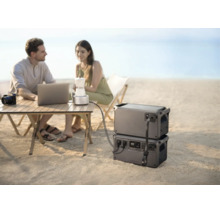 Tragbare Powerstations im Einsatz am Strand, versorgen Laptop und Kaffeemaschine auf einem Campingtisch mit Strom.