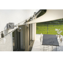 Wandhalterung für ein Sonnensegel mit Edelstahlseil und Lichterkette über einer Terrasse.
