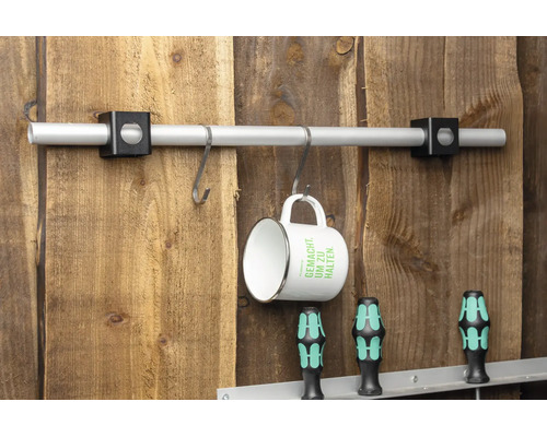 Aluminiumrohr mit zwei schwarzen Haltern an einer Holzwand montiert, mit S-Haken und einer Tasse.