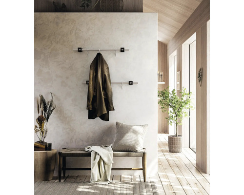 Moderne Wandgarderobe mit zwei Edelstahlstangen im hellen Flur mit Holzelementen, einer Sitzbank und einer Zimmerpflanze.