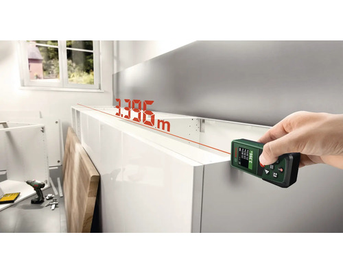 Ein digitaler Laserentfernungsmesser von Bosch wird verwendet, um die Länge eines Küchenschranks in einem Raum zu messen.