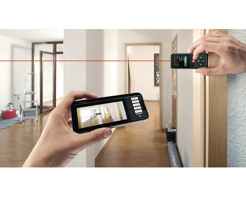 Ein digitaler Bosch Laser Entfernungsmesser wird in einem Innenraum zur Messung genutzt und überträgt die Daten per App auf ein Smartphone.