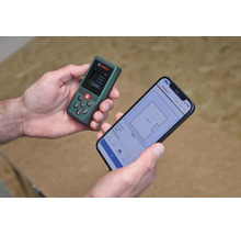 Ein Bosch Laserentfernungsmesser in der Hand verbunden mit einer Smartphone App zur digitalen Grundrissplanung.