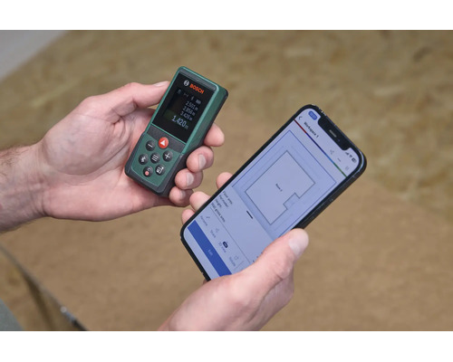 Ein Bosch Laserentfernungsmesser in der Hand verbunden mit einer Smartphone App zur digitalen Grundrissplanung.