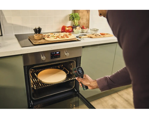 Person misst mit einem Bosch Thermodetektor die Temperatur eines Pizzasteins in einem Backofen in einer modernen Küche.