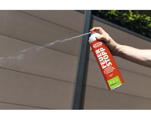 Eine Hand betätigt ein ABUS Feuerlöschspray Feuer Stopp, das einen Sprühstrahl abgibt.