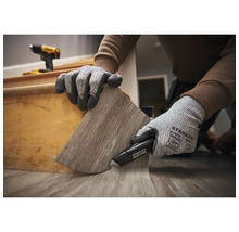 Person verwendet ein Stanley Cuttermesser und Schutzhandschuhe zum Zuschneiden von Vinylbodenbelag an einer Treppenstufe