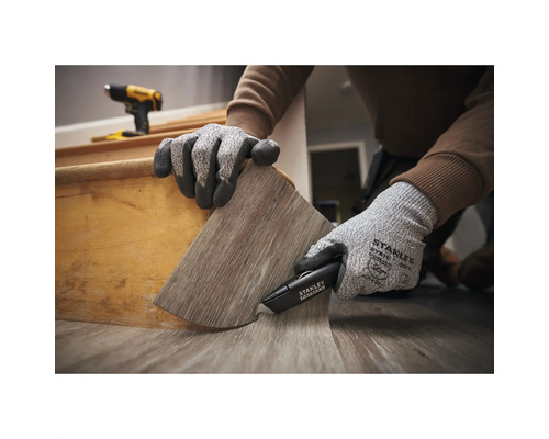 Person verwendet ein Stanley Cuttermesser und Schutzhandschuhe zum Zuschneiden von Vinylbodenbelag an einer Treppenstufe