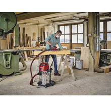 Handwerker schleift Holzbalken in Werkstatt mit Einhell Nass Trockensauger verbunden mit Einhell Logo Schleifgerät.