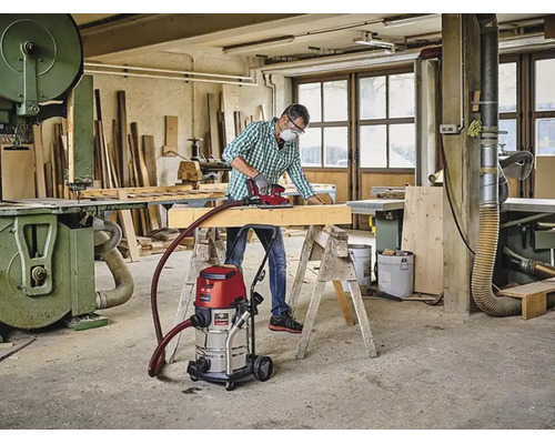 Handwerker schleift Holzbalken in Werkstatt mit Einhell Nass Trockensauger verbunden mit Einhell Logo Schleifgerät.
