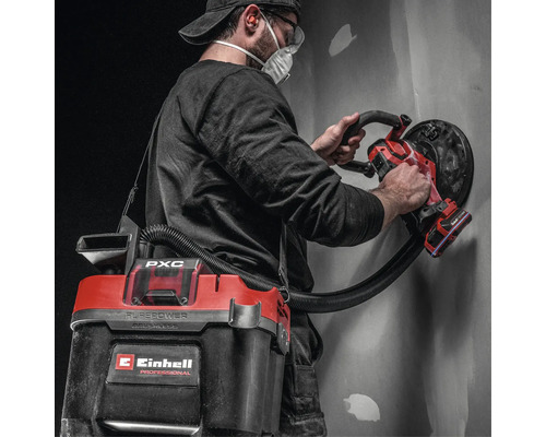 Handwerker mit Einhell Akku Wand- und Deckenschleifer und angeschlossenem Akku-Nass-Trockensauger bei der Bearbeitung einer Wand.