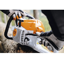 Person mit Arbeitshandschuhen bedient eine Stihl Motorsäge bei Forstarbeiten