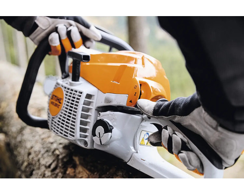 Person mit Arbeitshandschuhen bedient eine Stihl Motorsäge bei Forstarbeiten