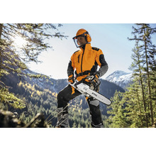 Forstarbeiter mit Stihl Motorsäge und Schutzausrüstung im Wald vor einer Bergkulisse.