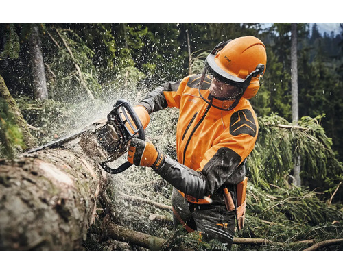 Forstarbeiter bei der Arbeit mit einer Stihl Motorsäge in einem Wald, trägt Schutzkleidung inklusive Helm mit Visier und Gehörschutz.