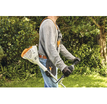 Eine Person trägt einen Stihl Freischneider mit einem bequemen Tragegurt im Garten für ergonomische Mäharbeiten.