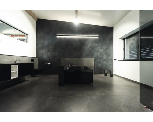Modernes Badezimmer mit freistehender Badewanne, dunkler Wandgestaltung, großflächigen Bodenfliesen und indirekter LED Beleuchtung.
