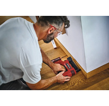 Handwerker befestigt Fußleisten mit einem Einhell Akku Nagler an der Wand.