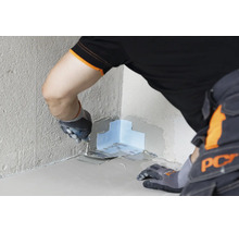 Handwerker beim Einarbeiten eines Dichtbandes in eine Innenecke mit einer Glättkelle zur professionellen Wand- und Bodenabdichtung.