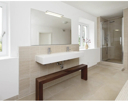 Modernes Badezimmer mit Doppelwaschbecken, Wandspiegel, Armaturen, Duschkabine und einer Holzbank vor einer hell gefliesten Wand.