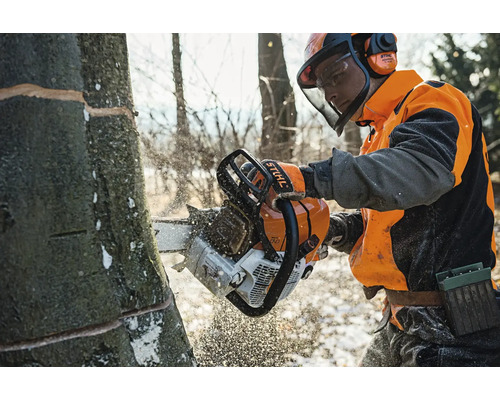 Forstarbeiter beim Sägen eines Baumes mit einer Stihl Motorsäge und vollständiger Schutzausrüstung im Wald.