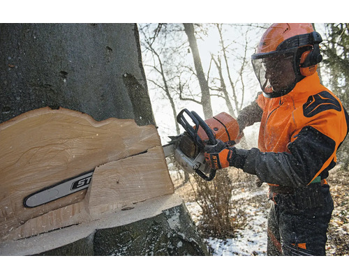 Forstwirt mit Stihl Motorsäge und Schutzausrüstung beim Fällen eines Baumes im Wald.
