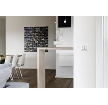 Ein weißer Jalousienschalter zur Rolladensteuerung, montiert an einer weißen Innenwand in einem modernen Wohnraum.
