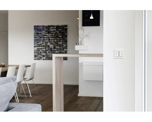 Ein weißer Jalousienschalter zur Rolladensteuerung, montiert an einer weißen Innenwand in einem modernen Wohnraum.