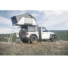 Ein Geländewagen mit montiertem Dachzelt und Leiter sowie einem faltbaren Solarmodul an der Seite in einer hügeligen Landschaft.