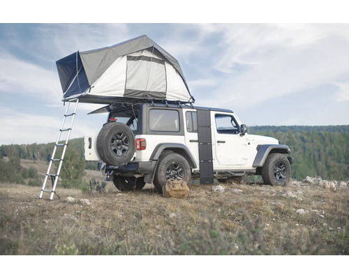 Ein Geländewagen mit montiertem Dachzelt und Leiter sowie einem faltbaren Solarmodul an der Seite in einer hügeligen Landschaft.