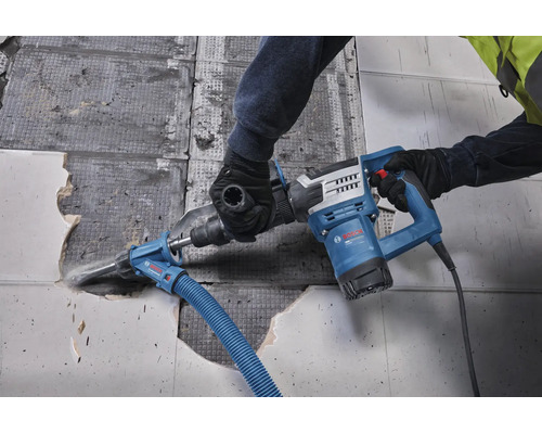 Handwerker entfernt Fliesen mit einem Bosch Professional Abbruchhammer mit angeschlossener Staubabsaugung auf einer Baustelle.
