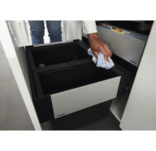 Einbauabfalltrennsystem von Blanco in einem Küchenschrank mit Person, die den Behälter mit einem Tuch reinigt.