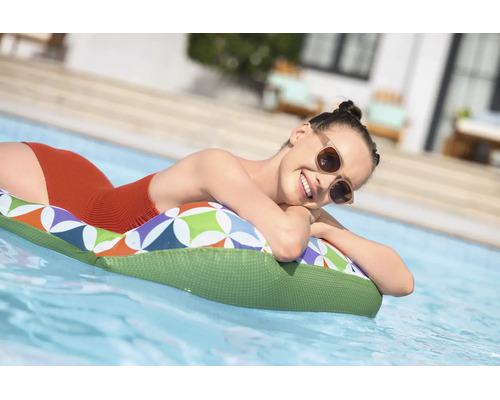 Eine Frau entspannt auf einer gemusterten Luftmatratze im Pool.