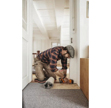 Handwerker kürzt einen Türrahmen mit einem Multifunktionswerkzeug in einer hellen Wohnumgebung.